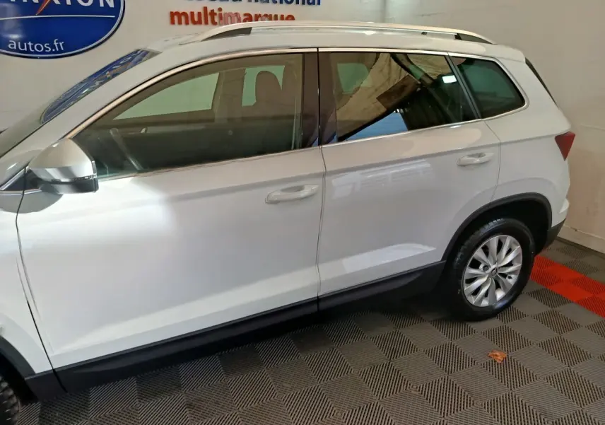 Vue latérale côté gauche d'un Skoda Karoq blanc 2024 avec jantes alliage et rétroviseurs électriques.