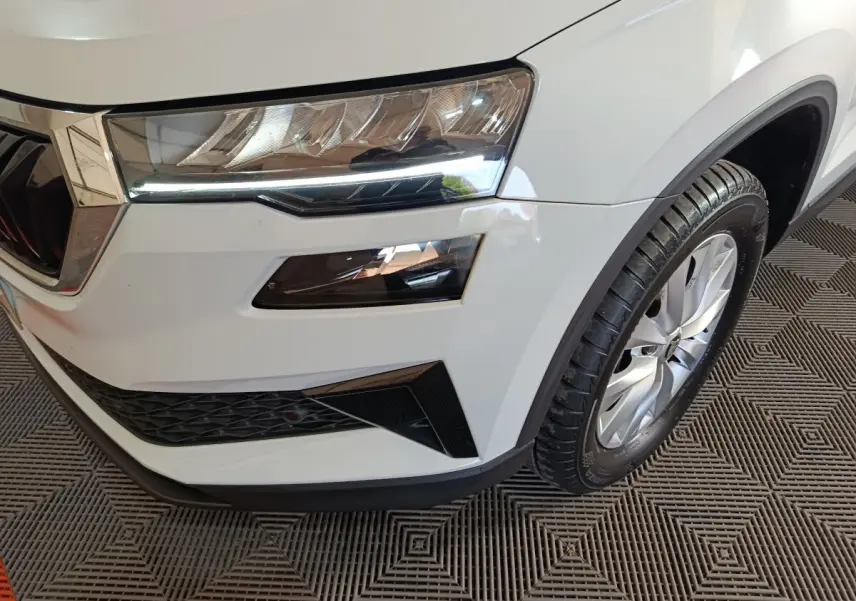 Gros plan sur l'avant droit blanc du Skoda Karoq 2.0 TDI avec phares LED et jante alliage visible.