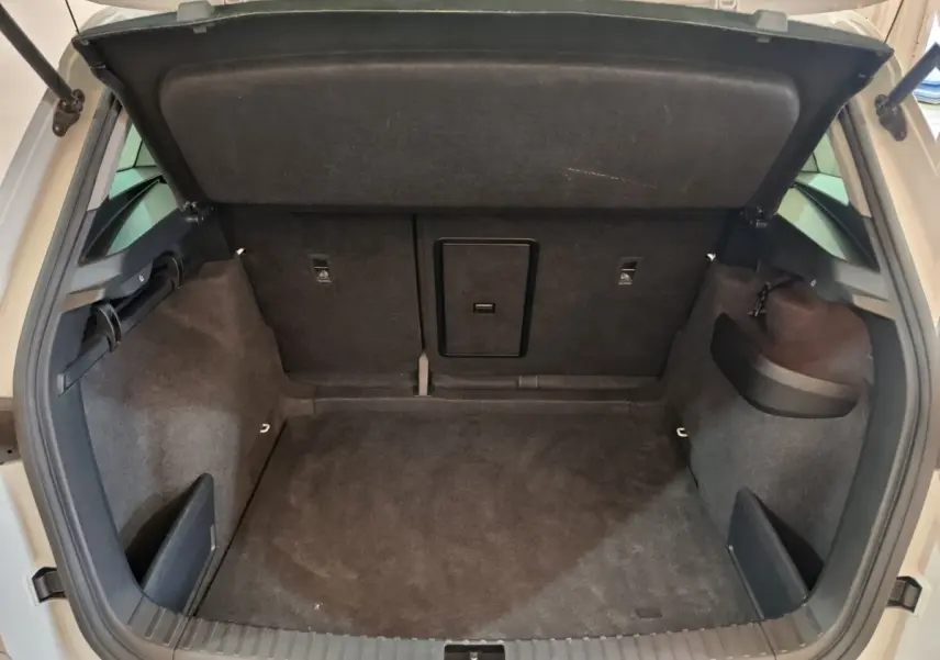 Coffre ouvert vu de l'arrière d'un SKODA KAROQ blanc, intérieur de coffre spacieux et revêtement noir.