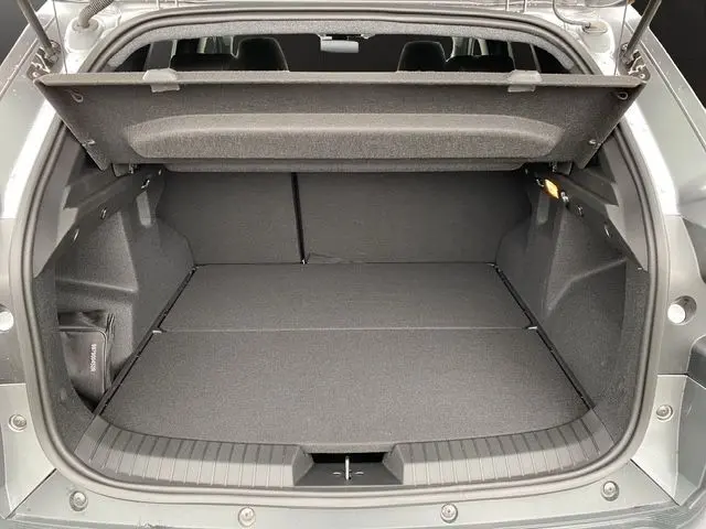 Coffre ouvert vu de l'arrière du Dacia Duster 1.6 Hybrid 140 gris schiste, montrant un espace de chargement spacieux et propre.