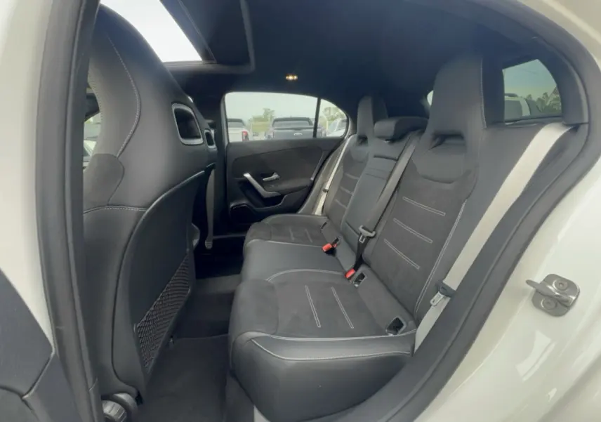 Vue intérieure arrière côté droit de la Mercedes Classe A 200D Exclusive Design avec sellerie cuir tissu noire et portières blanches.