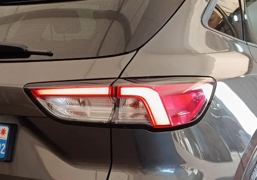 Feu arrière droit allumé d’un Ford Kuga gris foncé, vue rapprochée du coin arrière du véhicule.