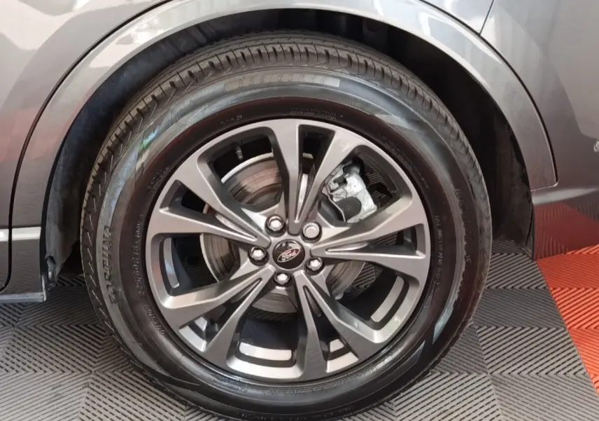 Gros plan sur la roue avant droite gris foncé du Ford Kuga 2023 avec jante alliage et logo Ford au centre.