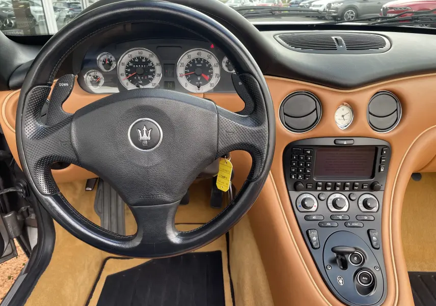 Intérieur cuir camel de la Maserati Spyder 2002, vue du tableau de bord et volant noir avec commandes intégrées.