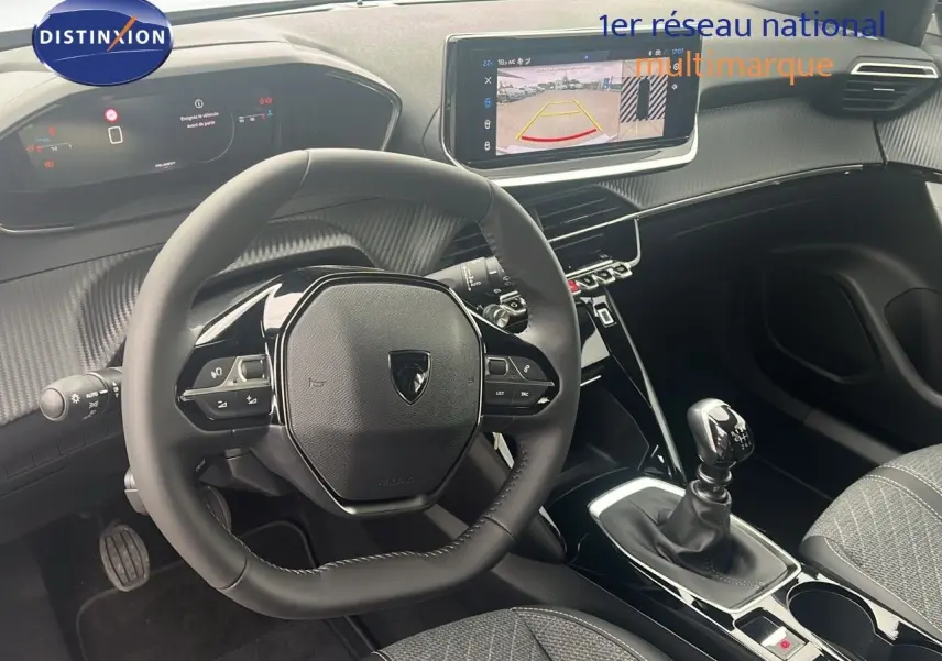 Vue intérieure du poste de conduite du Peugeot 2008 blanc, avec volant compact, écran tactile et levier de vitesse manuel.