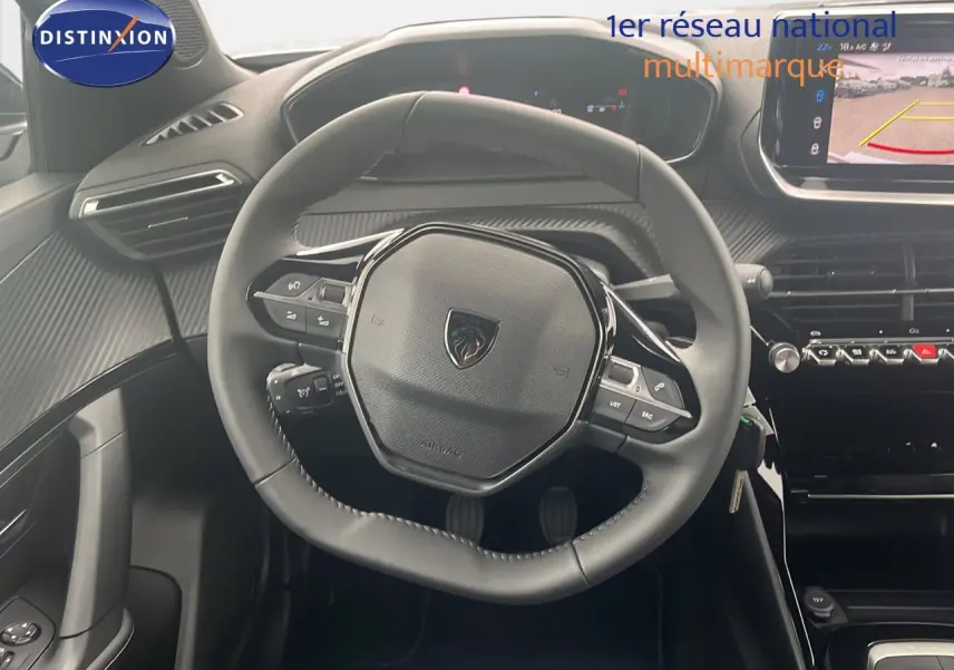 Vue centrée sur le volant cuir noir du Peugeot 2008 2025, avec tableau de bord digital et écran multimédia en arrière-plan.