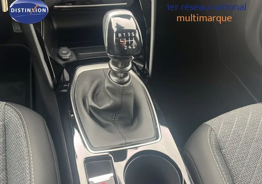 Le levier de vitesse manuel de la Peugeot 2008 blanc Okenite, entouré de sièges en tissu gris et cuir noir.