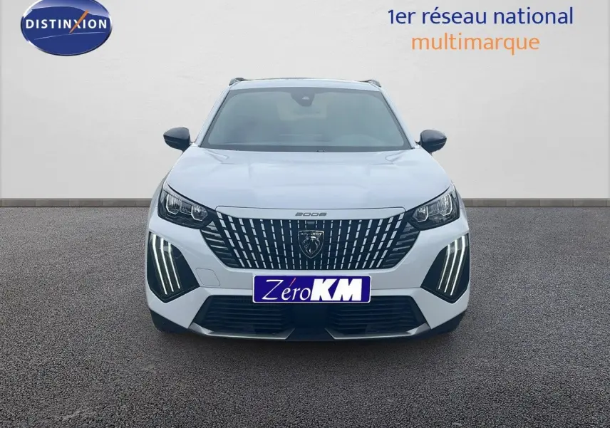 Vue frontale d'un Peugeot 2008 blanc Okenite Metal avec feux LED verticaux allumés sur un sol gris.