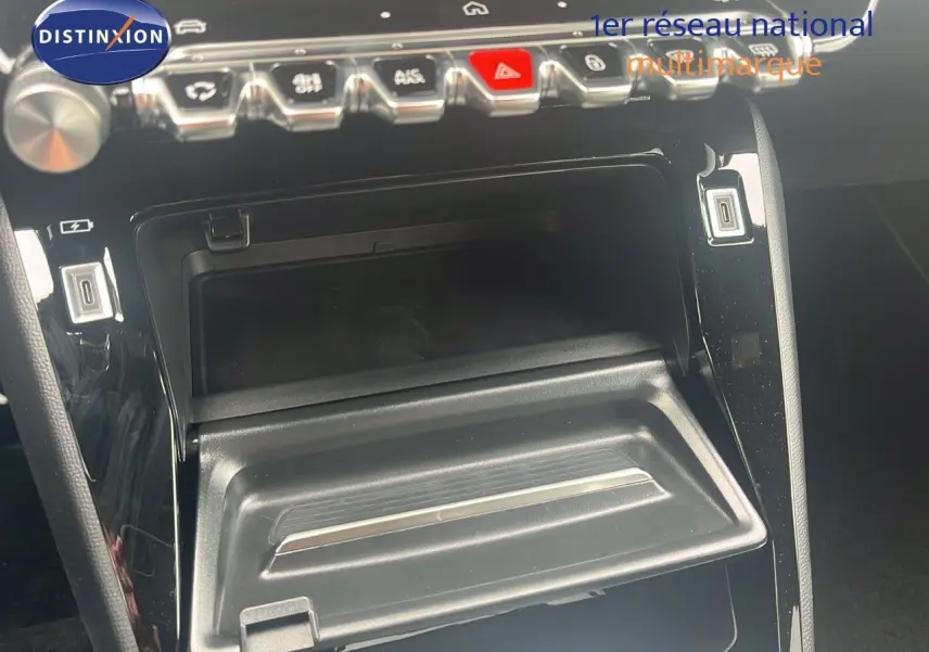 Intérieur de la Peugeot 2008 2025, vue rapprochée de la console centrale avec commandes et rangement ouvert noir brillant.