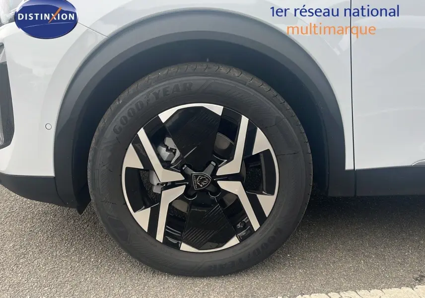 Gros plan sur la roue avant droite d'un Peugeot 2008 blanc Okenite Metal avec jante noire et argentée au design moderne.