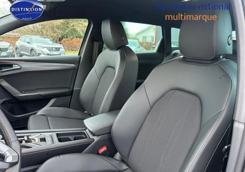 Vue intérieure de face des sièges avant en cuir gris foncé de la CUPRA LEON ST 1.5 etsi hybrid 2025 avec accoudoir central.