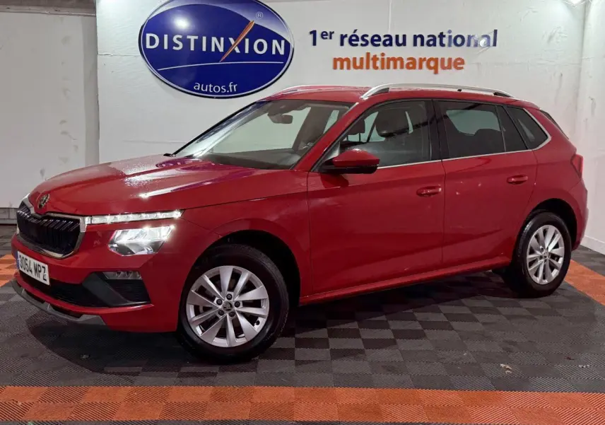 Vue latérale gauche d'un Skoda Kamiq rouge 2024 avec phares LED et jantes alliage en intérieur showroom.