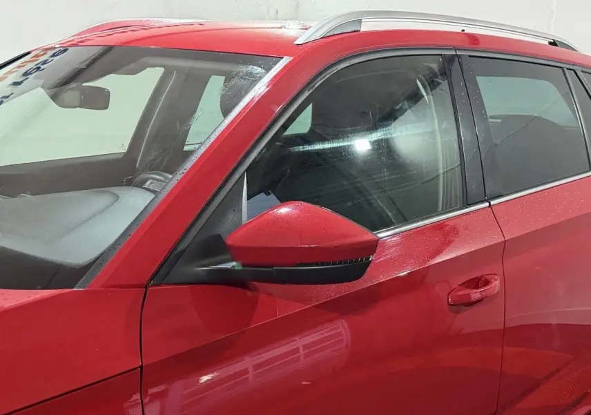 Vue côté gauche rapprochée du SKODA KAMIQ rouge 2024, mettant en valeur la portière et le rétroviseur assorti.