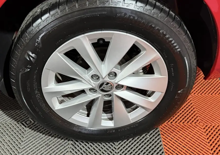 Gros plan sur la roue avant droite d’un Skoda Kamiq rouge, mettant en valeur la jante argentée au design moderne.