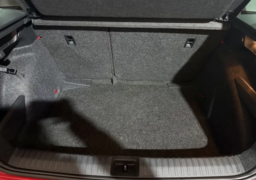 Coffre ouvert vu de l'arrière d'un Skoda Kamiq rouge 2024, espace de chargement tapissé gris.