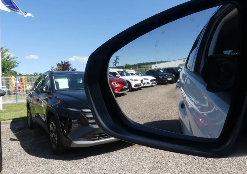 Vue dans le rétroviseur côté droit d’un Opel Grandland blanc métallisé en 2024, avec plusieurs voitures en arrière-plan.