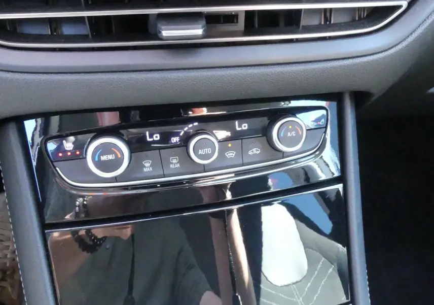 Vue rapprochée de la console centrale noire brillante avec commandes de climatisation et chauffage sur Opel Grandland blanc.