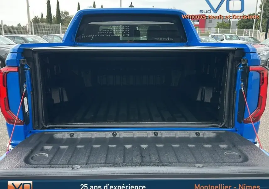 Vue arrière du coffre ouvert du pick-up Volkswagen Amarok Simple Cabine bleu, montrant la benne spacieuse et protégée.