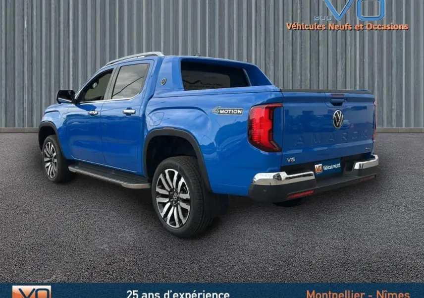 Vue 3/4 arrière droite d’un Volkswagen Amarok Aventura bleu avec jantes alliage 21 pouces et marchepieds visibles.