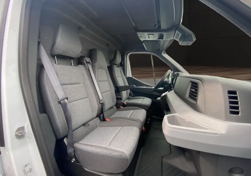Vue intérieure côté gauche du Renault Master blanc 2025, montrant la banquette passager grise et le tableau de bord clair.