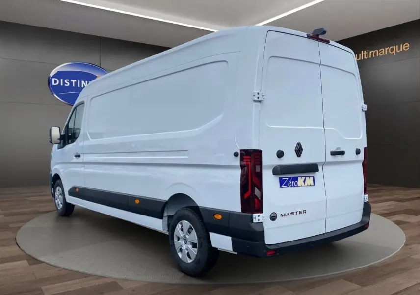 Vue 3/4 arrière droite d’un Renault Master blanc avec portes arrière tôlées et enjoliveurs noirs au sol en showroom.