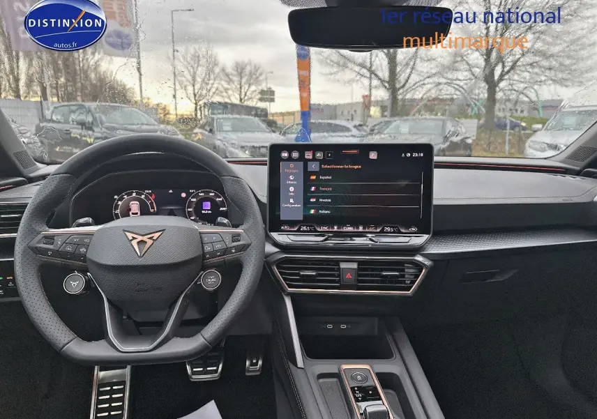 Intérieur de la CUPRA Leon ST 2025 vu de face, volant cuir sport et écran tactile central allumé.