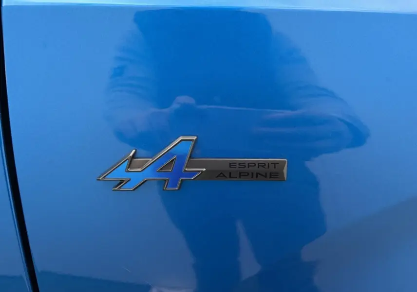 Gros plan sur le badge Esprit Alpine bleu et noir sur la carrosserie Summit Blue d'une Renault Rafale 2025.