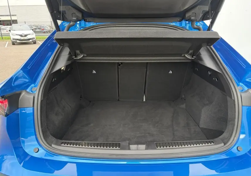 Coffre ouvert vu de l'arrière d'une Renault Rafale Summit Blue, montrant l'espace de chargement vide et les finitions intérieures noires.