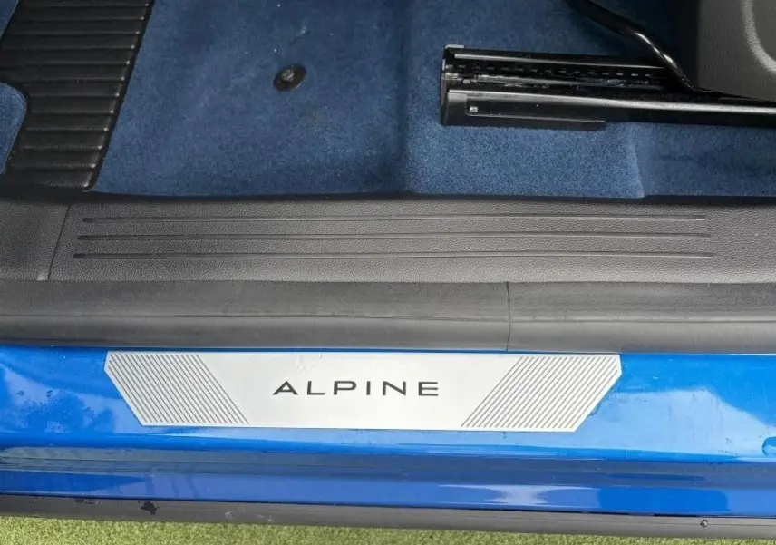 Gros plan sur la plaque de seuil de porte "ALPINE" sur un Renault Rafale Summit Blue, intérieur avec moquette bleue.