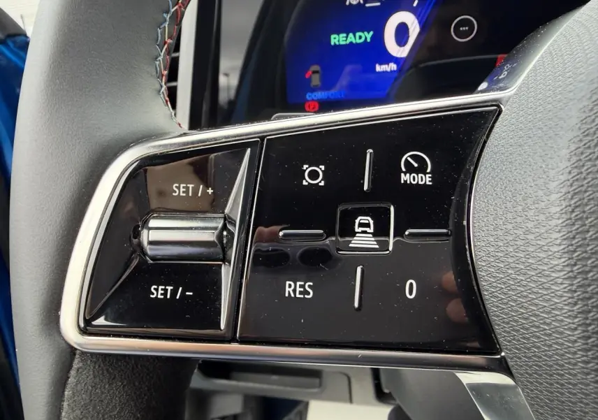 Gros plan sur les commandes au volant du Renault Rafale Summit Blue, affichage digital bleu en arrière-plan.