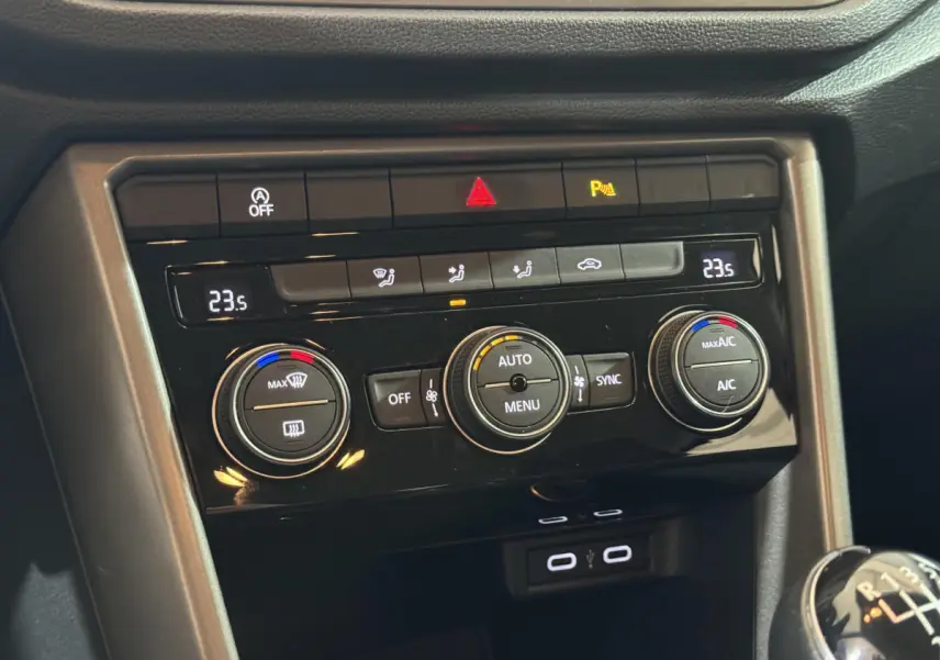 Gros plan sur la console centrale du Volkswagen T-Roc gris foncé, montrant la climatisation digitale et la commande de boîte manuelle.