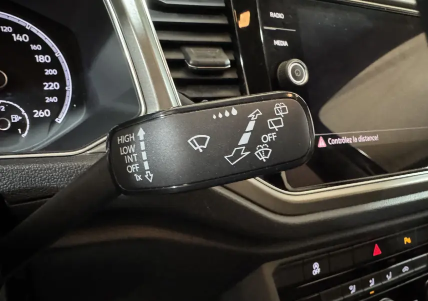 Gros plan sur la commande d’essuie-glace du Volkswagen T-Roc 2.0 TDI 115 Lounge Business, tableau de bord noir visible.