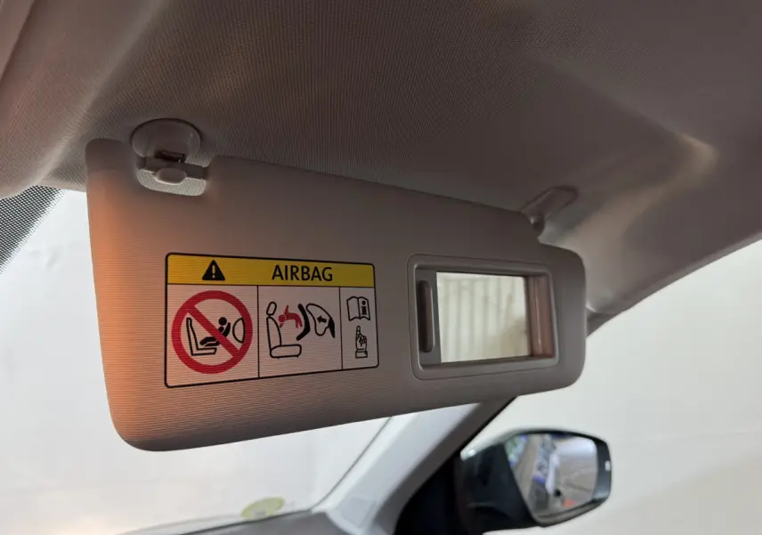 Détail du pare-soleil côté conducteur avec miroir et avertissement airbag dans un Volkswagen T-Roc gris foncé.