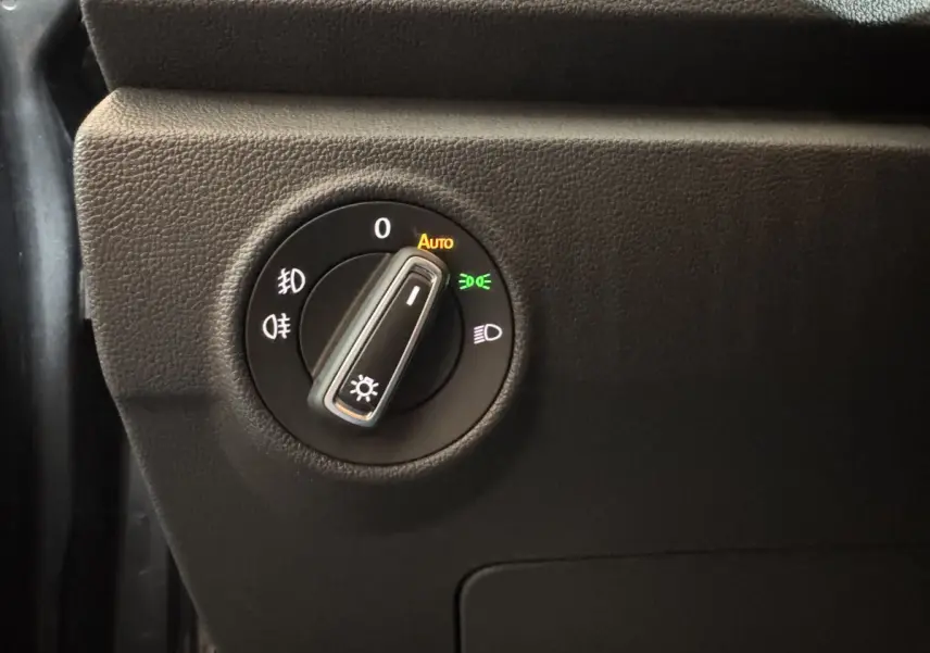 Gros plan sur le bouton de commande des phares du Volkswagen T-Roc gris foncé, avec réglage sur automatique.