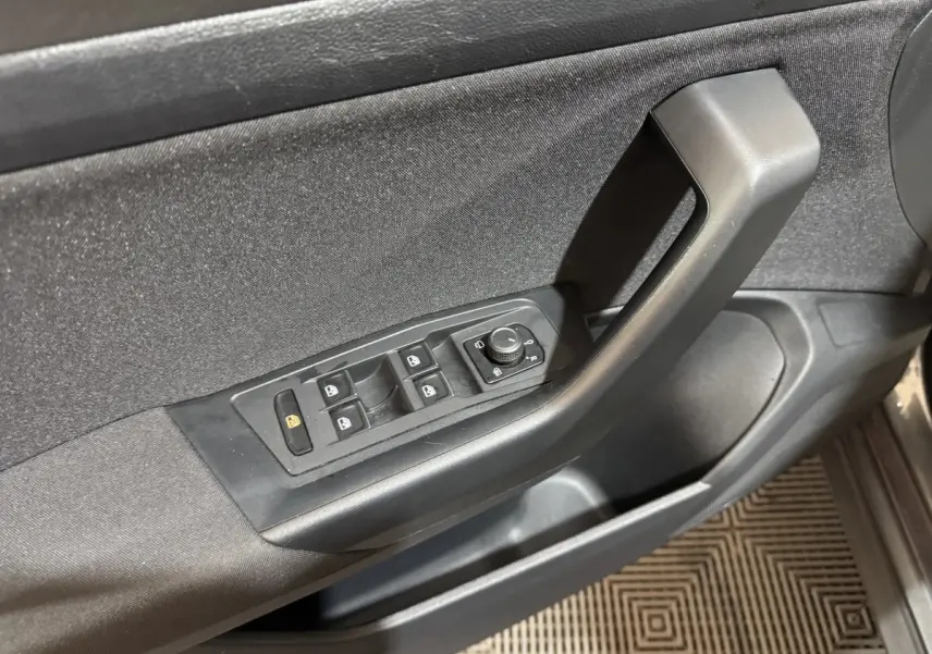 Panneau de porte côté conducteur du Volkswagen T-Roc gris foncé, avec commandes électriques des vitres et rétroviseurs.