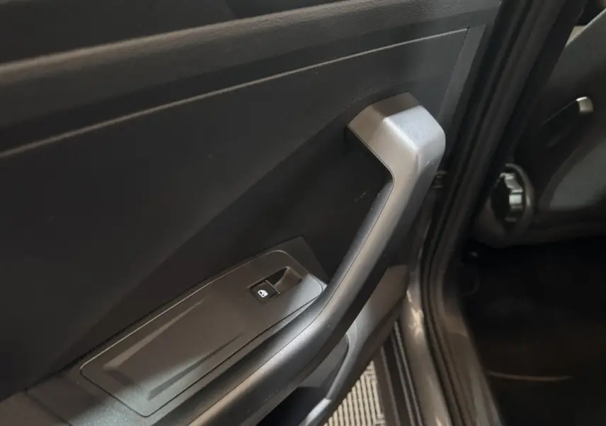 Gros plan sur la poignée intérieure côté gauche gris foncé du Volkswagen T-Roc 2021 avec bouton de lève-vitre intégré.