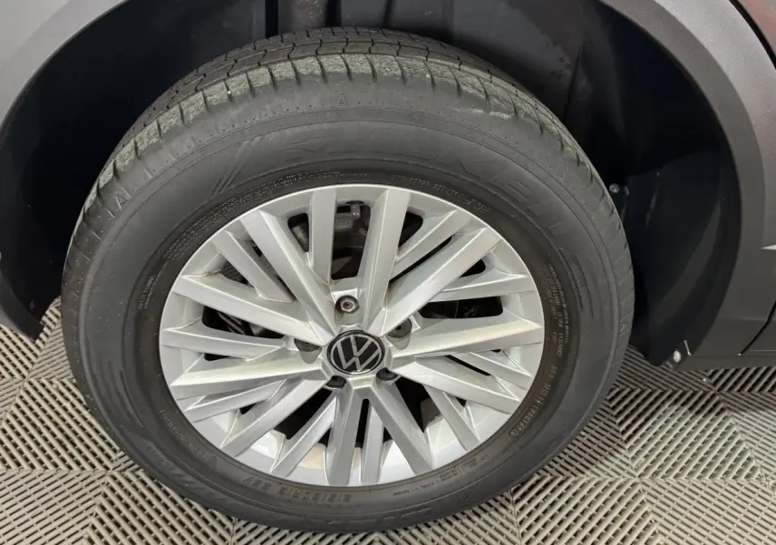 Gros plan sur la roue avant droite avec jante alliage argentée du Volkswagen T-Roc gris foncé.