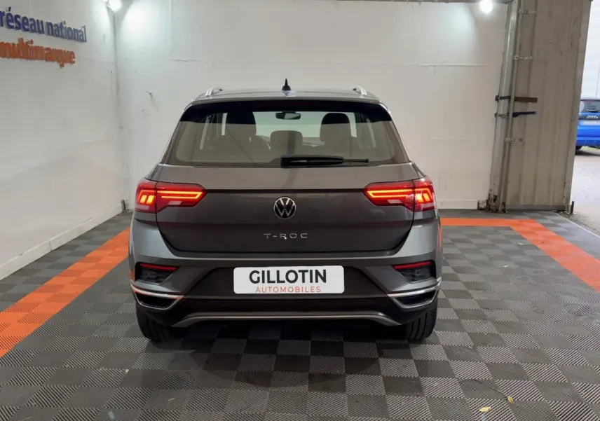 Vue arrière d'un Volkswagen T-Roc gris foncé 2021 avec feux LED allumés dans un garage.