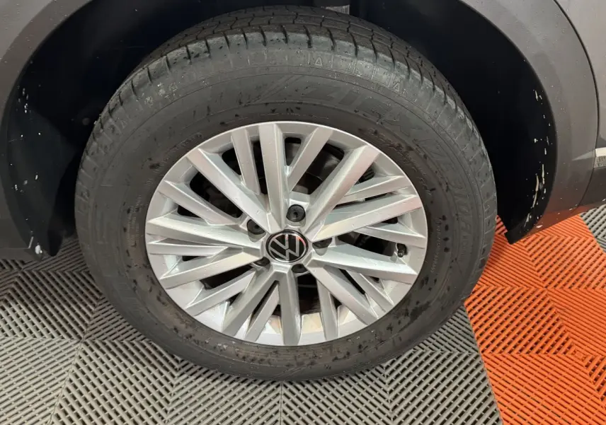 Gros plan sur la roue avant droite du Volkswagen T-Roc gris foncé avec jante alliage et logo VW au centre