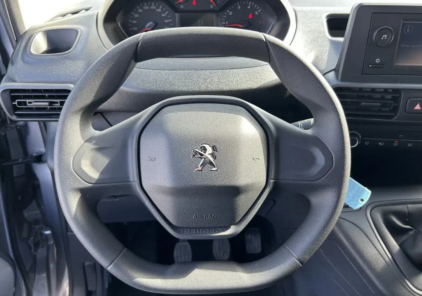 Vue intérieure centrée sur le volant Peugeot noir du Dangel Partner 4x4, avec tableau de bord et console visibles.