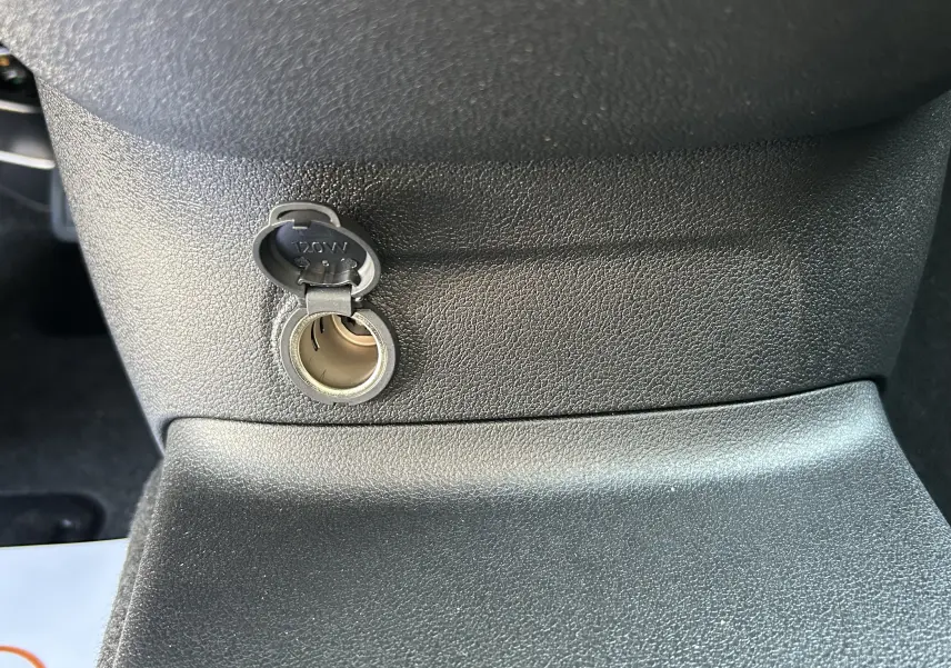 Prise 12V ouverte sur la console centrale noire du Peugeot Partner Dangel 4x4, vue rapprochée intérieure.