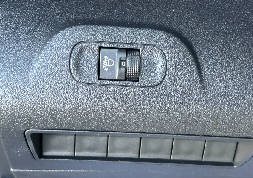 Gros plan sur le réglage d'inclinaison des phares dans l'habitacle du DANGEL Peugeot Partner gris Artense.