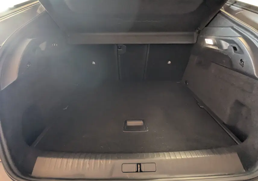 Coffre ouvert du Peugeot 3008 gris 2024, vue intérieure montrant un espace de chargement propre et éclairé.