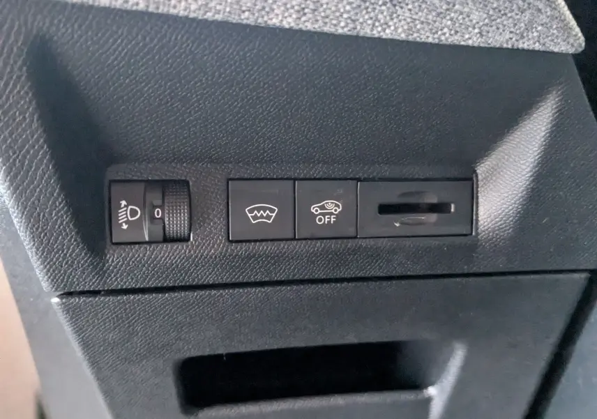Détail intérieur montrant les commandes de réglage des phares, dégivrage et désactivation de l'assistance au maintien de voie sur Peugeot 3008 gris.