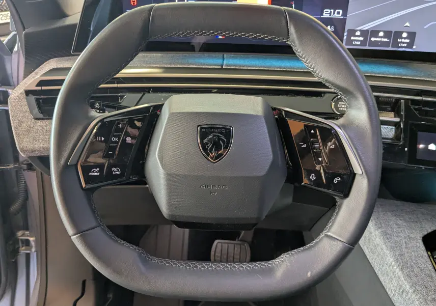 Vue frontale centrée sur le volant noir du Peugeot 3008 1.2 136ch hybrid allure avec logo lion et commandes tactiles intégrées.