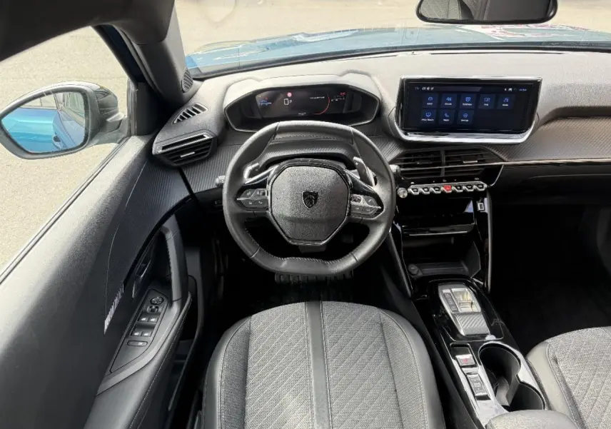 Vue intérieure du poste de conduite du Peugeot 2008 2025 bleu obsession, avec volant compact et écran tactile central.