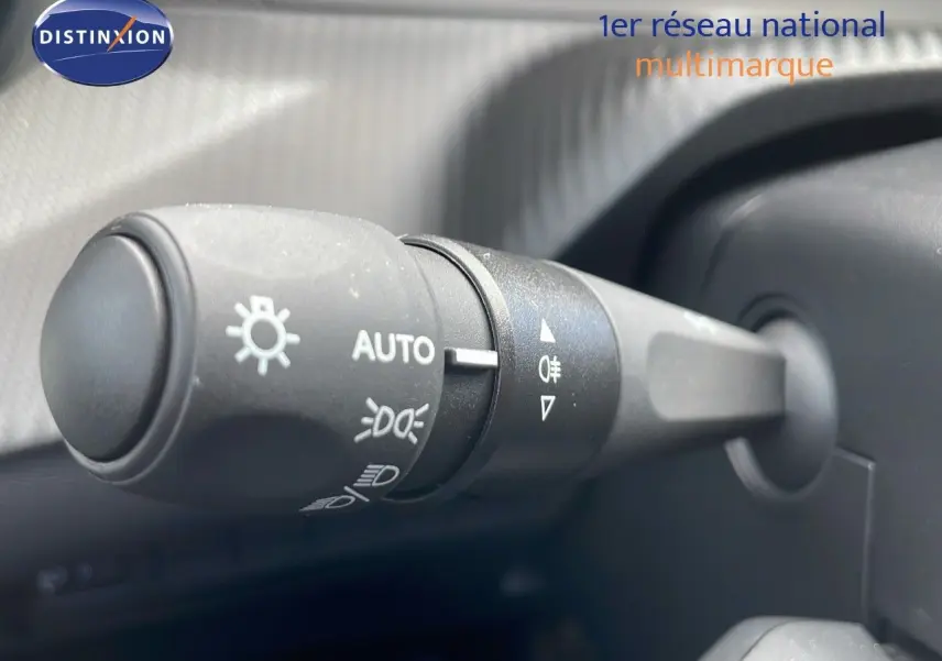 Gros plan sur la commande des feux automatiques à gauche du volant dans l'habitacle d'une Peugeot 2008 noire.