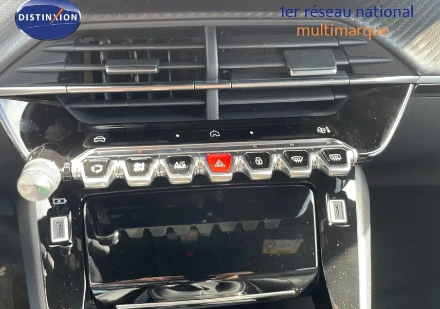 Gros plan sur la console centrale noire brillante du Peugeot 2008 2025, avec boutons de commande et aérateurs visibles.