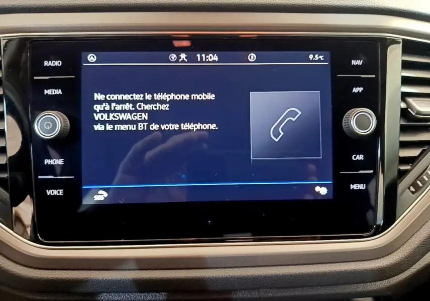 Écran tactile central du Volkswagen T-Roc 2021 affichant un message de connexion Bluetooth, entouré de boutons fonctionnels.