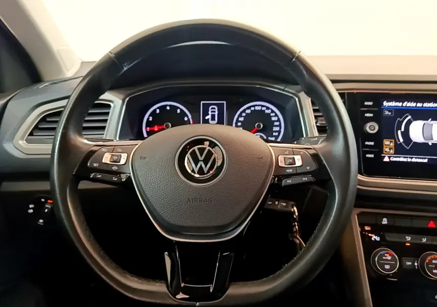 Vue rapprochée du volant cuir noir multifonctions du Volkswagen T-Roc 2021 avec tableau de bord numérique et écran tactile.